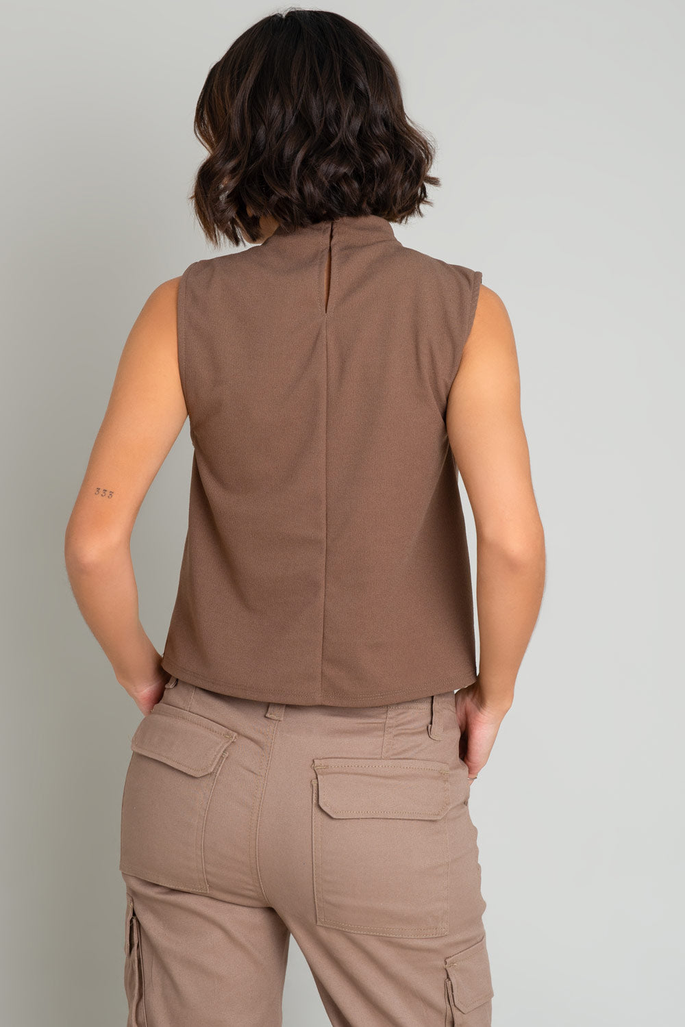 Blusa sin mangas de fit recto, cuello mock con detalles plisados y cierre posterior con botón y ojal