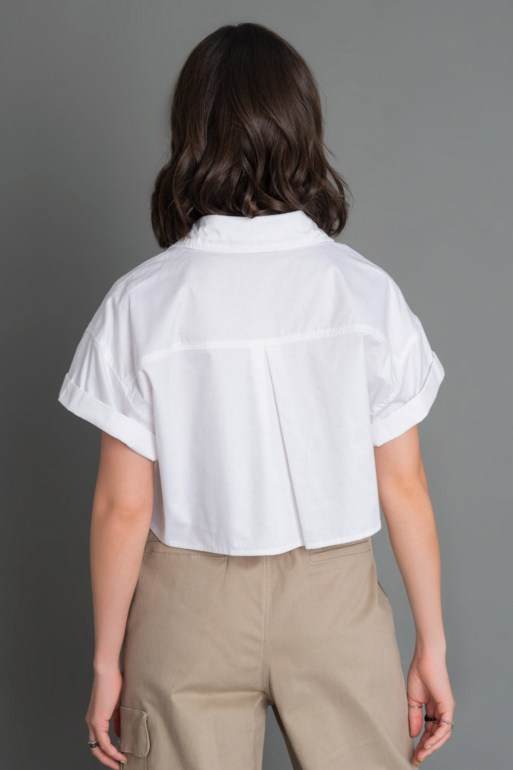 Camisa corta de fit ligeramente oversized, manga corta con doblez en borde, cuello camisero, bolsillos frontales en bajo y pinza de amplitud en espalda.