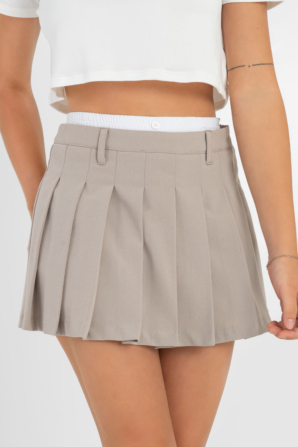 Falda corta tableada de cintura alta, pretina con trabillas y detalle de boxer en contraste. Cierre lateral con cremallera oculta.