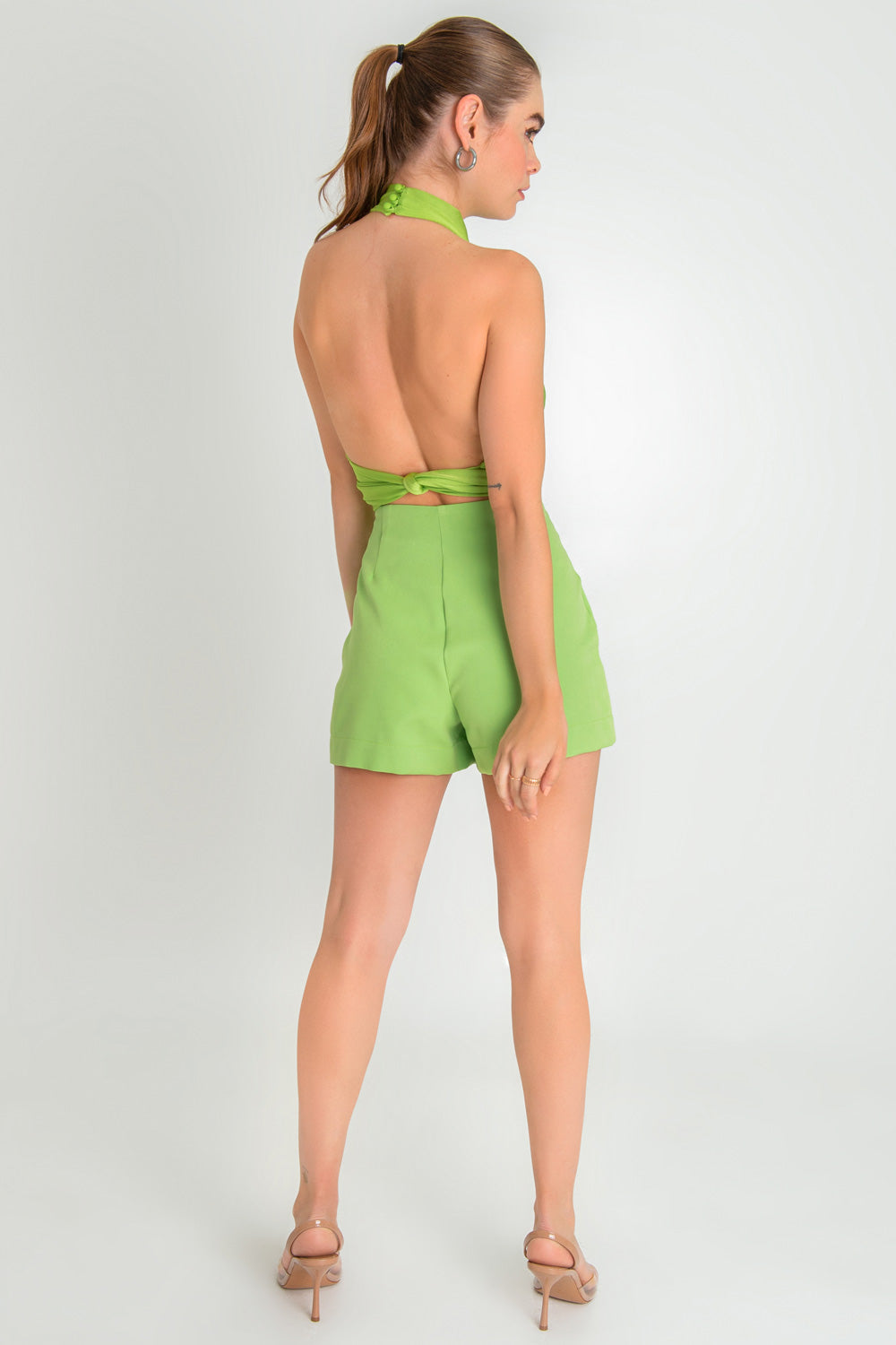 Falda short de fit ajustado, cintura alta, botones frontales decorativos en contraste y cruce frontal con abertura. Cierre lateral con cremallera oculta.