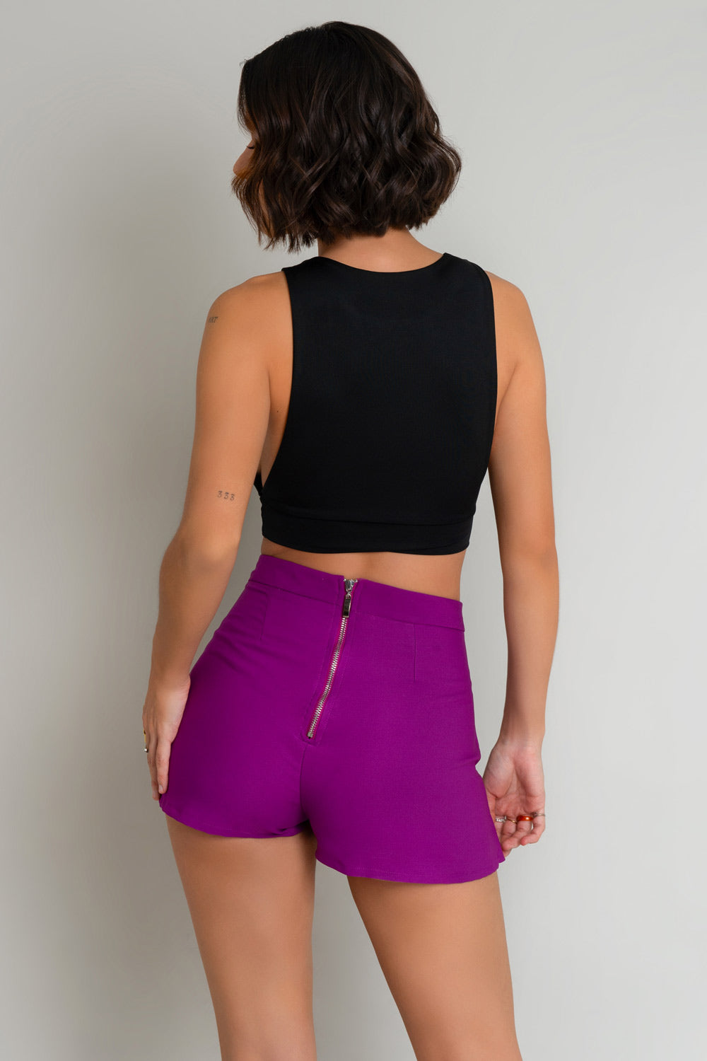 Falda short asimétrico de cintura alta, pretina y cierre posterior con cremallera visible.