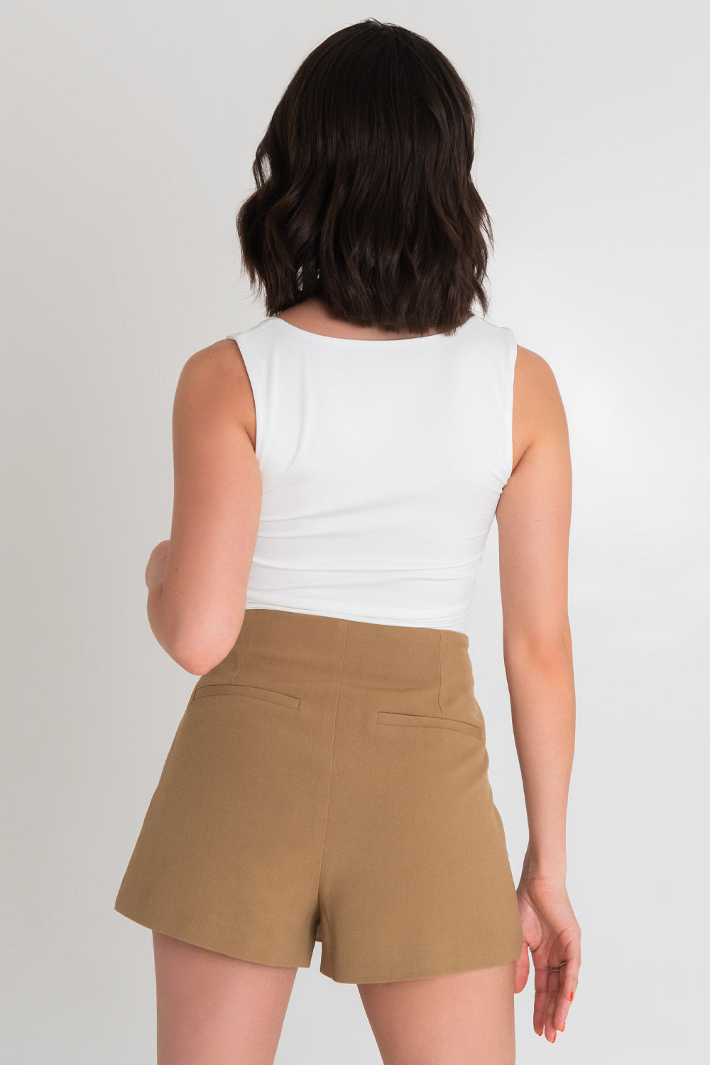 Falda short corto cruzado de fit ajustado, cintura alta, vivos decorativos posteriores y bajo curveado frontal. Cierre lateral con cremallera oculta.