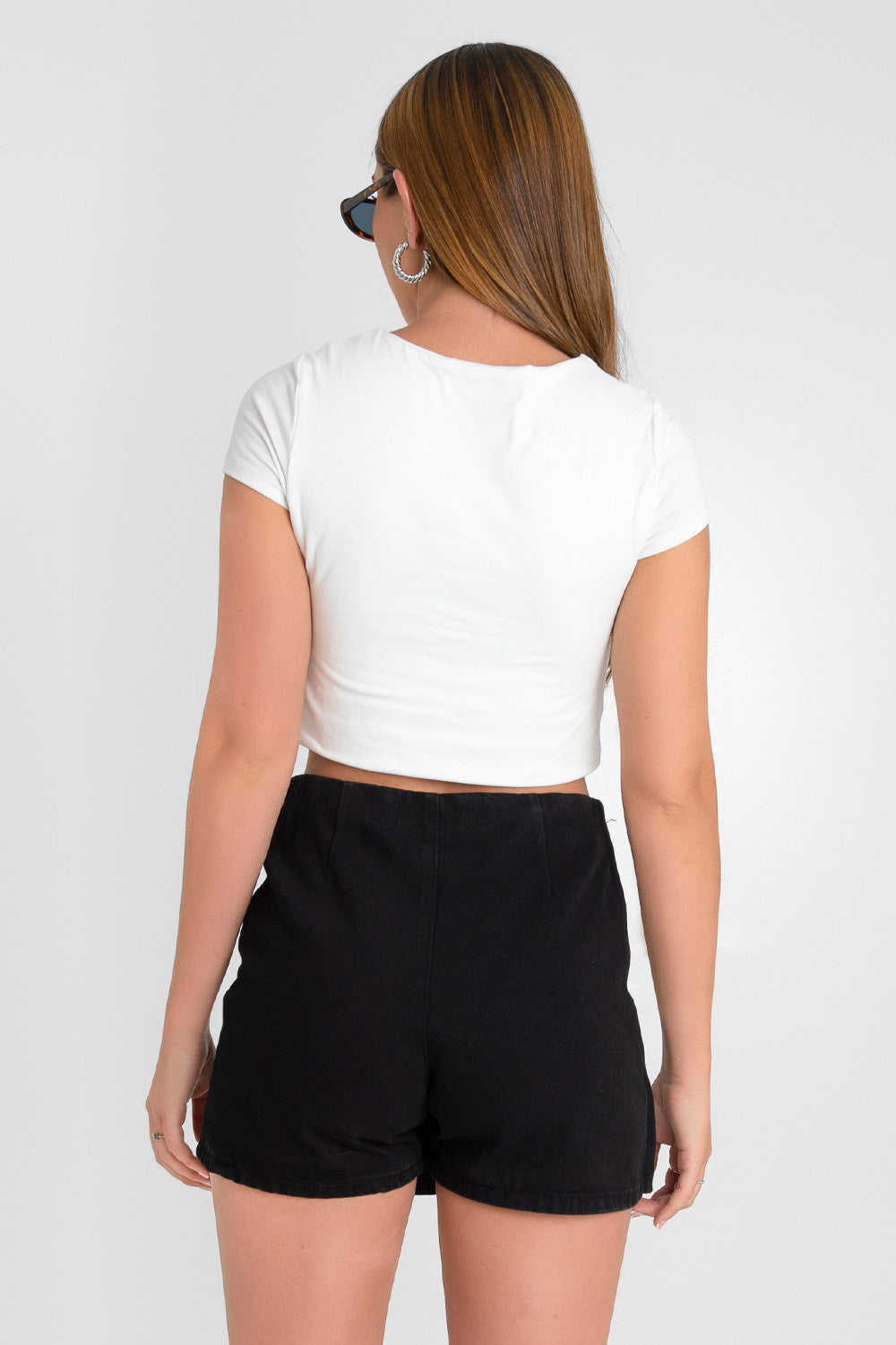Falda short corto de fit ajustado, cintura alta, cruce frontal con plisados decorativos y cierre lateral con cremallera oculta.