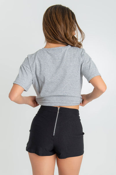 Falda short de fit ajustado, cintura alta con pretina, plisados frontales con abertura y cierre posterior con cremallera visible en contraste.
