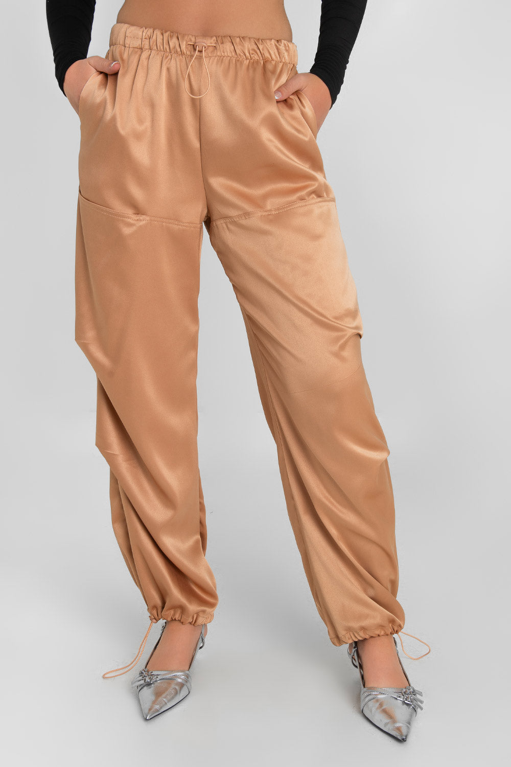 Pantalón parachute satinado de cintura alta con pretina elástica y jareta ajustable, de pierna amplia, plisados decorativos frontales, detalle de bajo con jaretas elásticas ajustables.