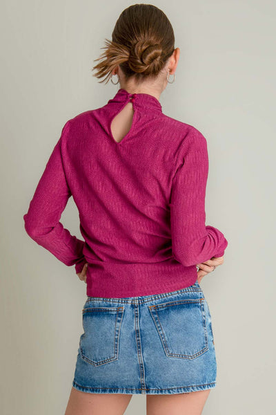 Jersey ligero de fit recto, cuello mock con plisados y manga larga. Detalle de plisados decorativos en costados. 