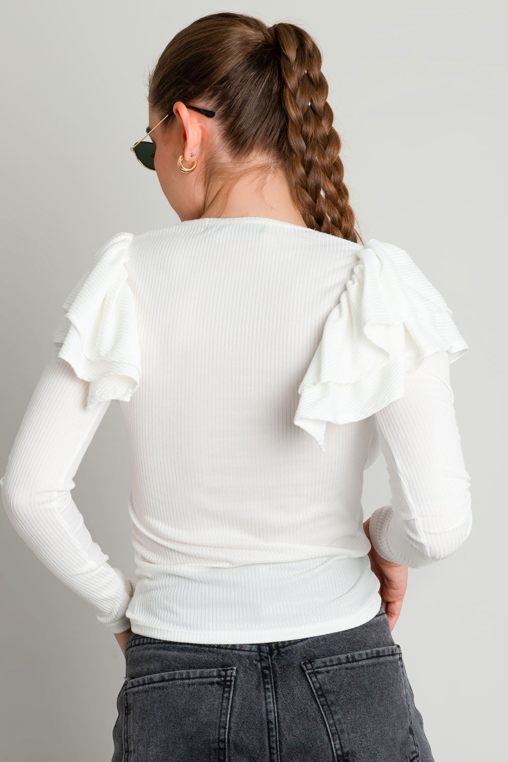 Top de fit ajustado, cuello redondo, manga larga y detalle de capas de olanes en hombros.