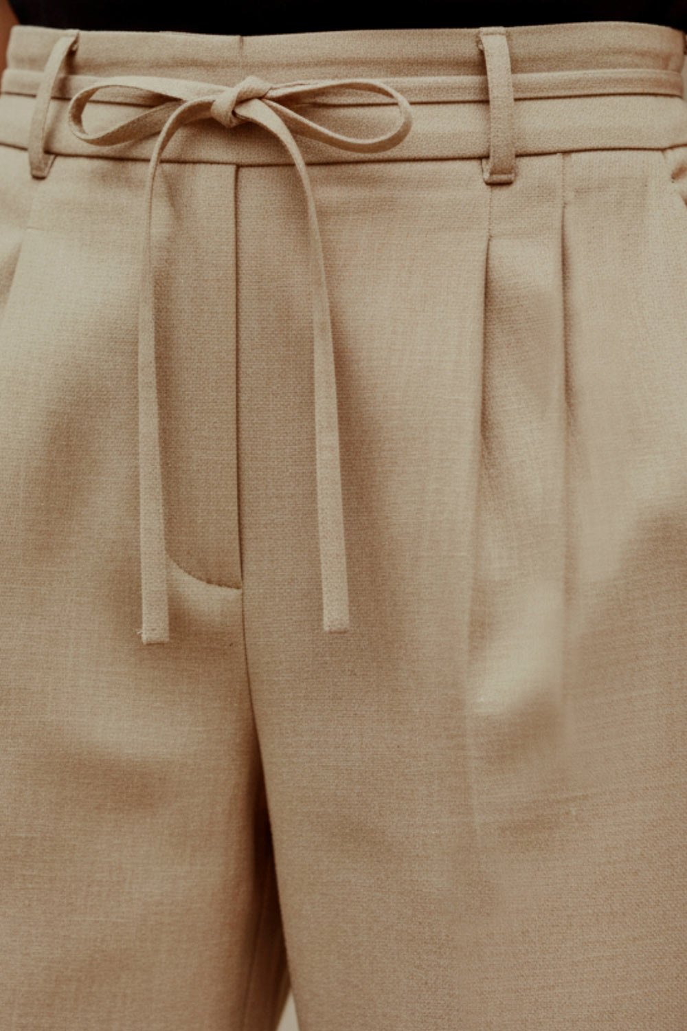 Pantalón de fit wide leg, cintura alta con pretina, trabillas y lazo amarrable, pinzas frontales y bolsillos delanteros. Cierre frontal con broche y cremallera ocultos. Detalle de doblez en bajo.