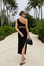 Vestido midi asimétrico de un hombro, fit ajustado, escote diagonal, sin mangas, plisado en costados, abertura lateral en bajo y cut out en espalda. Cierre posterior con cremallera oculta.