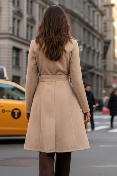 Abrigo abierto de gamuza, corte en a, con solapa y hombreras, manga larga, bolsillos delanteros ocultos, trabillas y cinturón amarrable del mismo tejido.