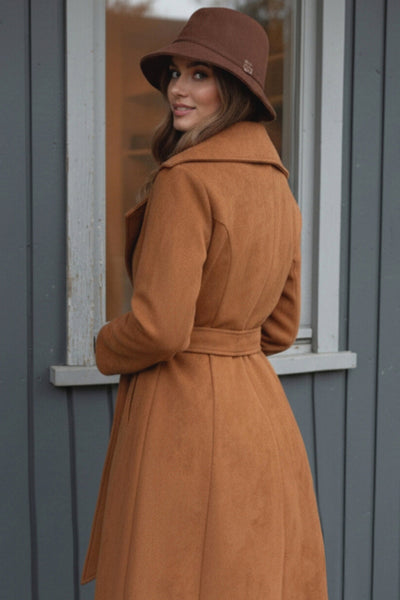 Abrigo abierto de gamuza, corte en a, con solapa y hombreras, manga larga, bolsillos delanteros ocultos, trabillas y cinturón amarrable del mismo tejido.