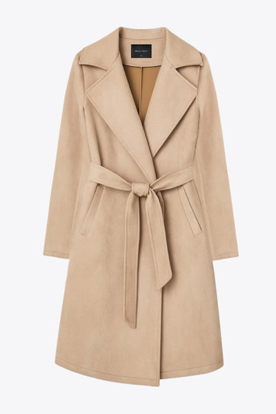 Abrigo abierto de gamuza, corte en a, con solapa y hombreras, manga larga, bolsillos delanteros ocultos, trabillas y cinturón amarrable del mismo tejido.