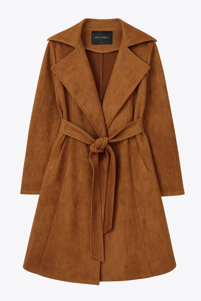 Abrigo abierto de gamuza, corte en a, con solapa y hombreras, manga larga, bolsillos delanteros ocultos, trabillas y cinturón amarrable del mismo tejido.