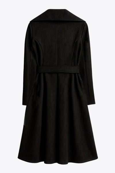 Abrigo abierto de gamuza, corte en a, con solapa y hombreras, manga larga, bolsillos delanteros ocultos, trabillas y cinturón amarrable del mismo tejido.