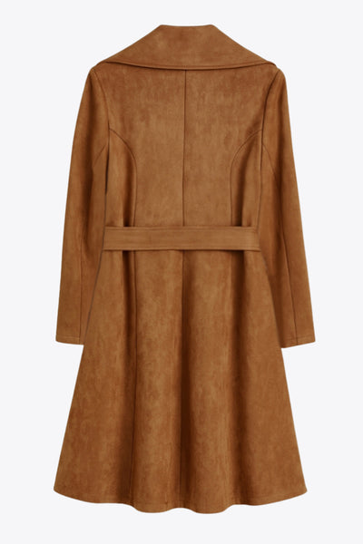 Abrigo abierto de gamuza, corte en a, con solapa y hombreras, manga larga, bolsillos delanteros ocultos, trabillas y cinturón amarrable del mismo tejido.