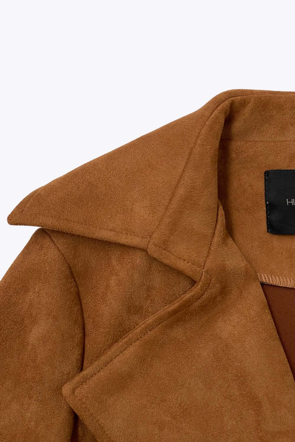 Abrigo abierto de gamuza, corte en a, con solapa y hombreras, manga larga, bolsillos delanteros ocultos, trabillas y cinturón amarrable del mismo tejido.