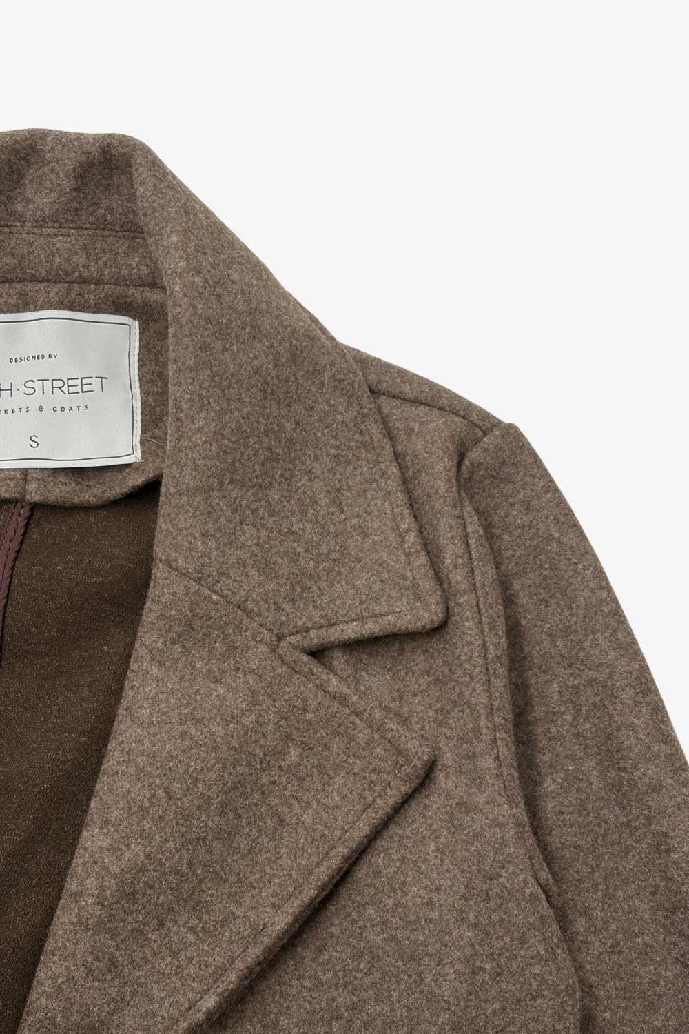 Abrigo de fit recto, con solapa, manga larga, bolsillos frontales con vivos, trabillas y cinturón amarrable del mismo tejido.