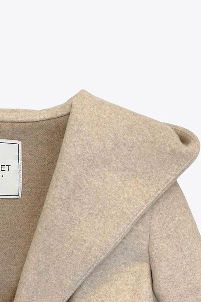 Abrigo de fit recto con capucha, manga larga y bolsillos delanteros. Detalle de trabillas y cinturón amarrable del mismo tejido.