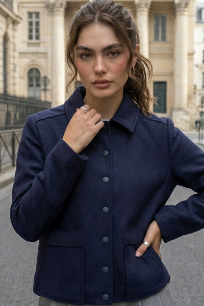 Abrigo corto de fit recto, manga larga, cuello solapa, bolsillos delanteros de parche con cartera y cierre frontal con hilera de botones en contraste.