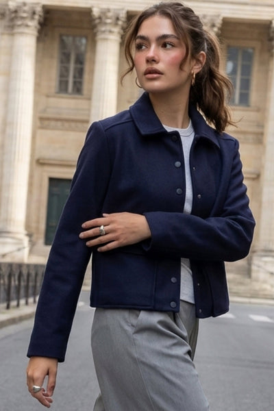 Abrigo corto de fit recto, manga larga, cuello solapa, bolsillos delanteros de parche con cartera y cierre frontal con hilera de botones en contraste.