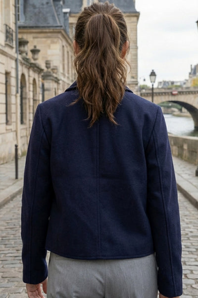 Abrigo corto de fit recto, manga larga, cuello solapa, bolsillos delanteros de parche con cartera y cierre frontal con hilera de botones en contraste.