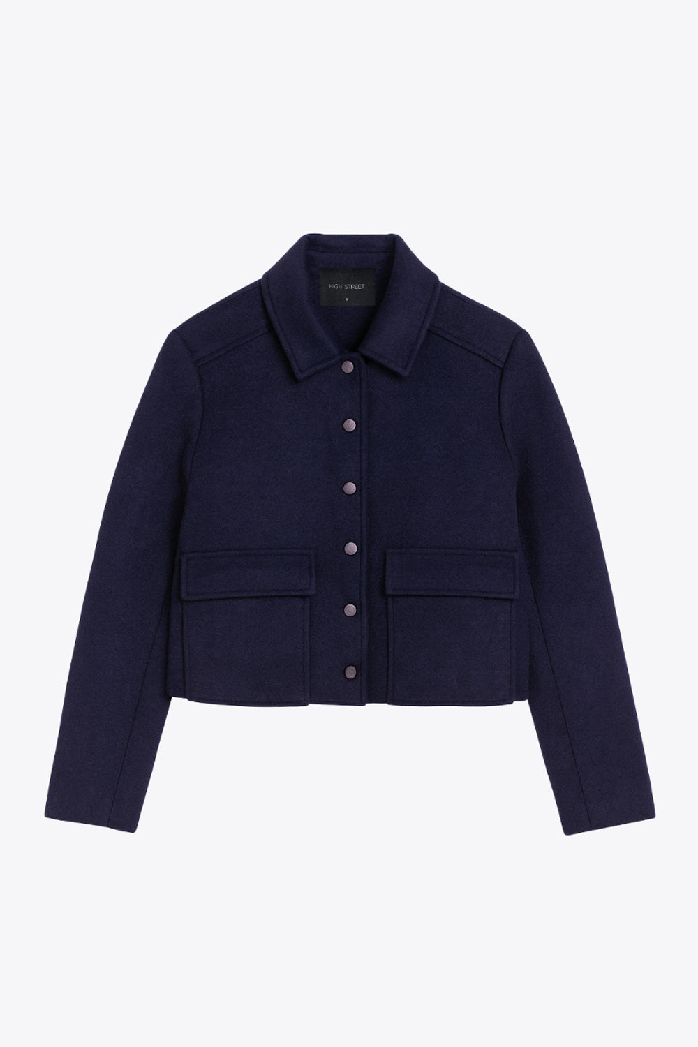 Abrigo corto de fit recto, manga larga, cuello solapa, bolsillos delanteros de parche con cartera y cierre frontal con hilera de botones en contraste.