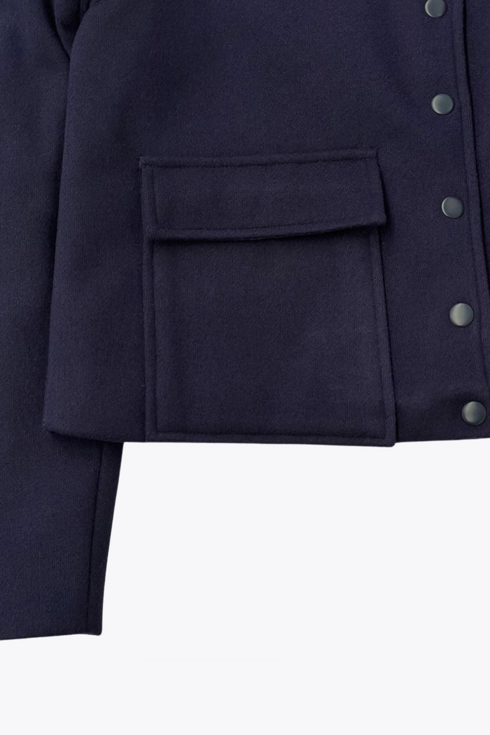 Abrigo corto de fit recto, manga larga, cuello solapa, bolsillos delanteros de parche con cartera y cierre frontal con hilera de botones en contraste.