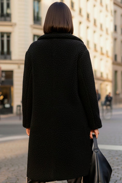 Abrigo largo de borreguillo, fit recto, con solapa, manga larga y bolsillos delanteros con vivos. Cierre frontal con botón en contraste.