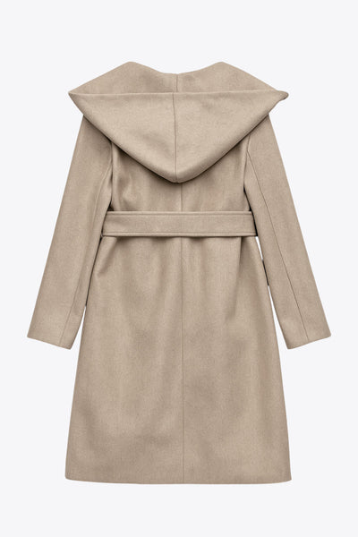 Abrigo largo de fit recto con capucha, manga larga y bolsillos delanteros. Detalle de trabillas y cinturón amarrable del mismo tejido.