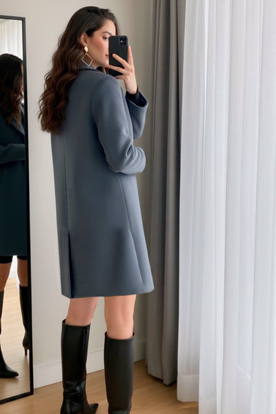 Abrigo largo de fit recto, con solapa, manga larga y bolsillos frontales con cartera. Cierre frontal con botón en contraste y detalle de abertura posterior.