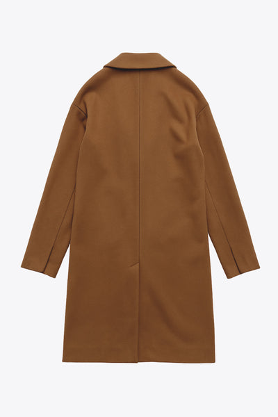 Abrigo largo de fit recto, con solapa, manga larga y bolsillos frontales con cartera. Cierre frontal con botón en contraste y detalle de abertura posterior.