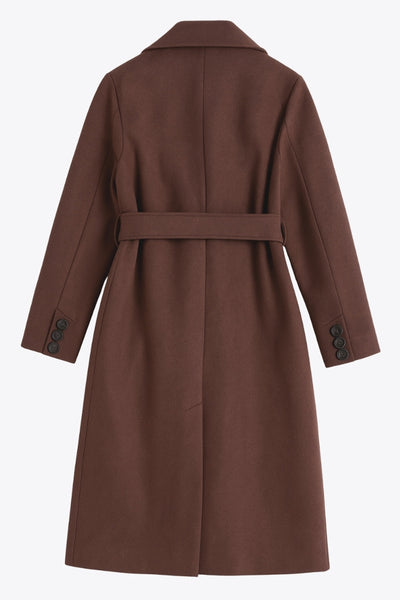 Abrigo largo de fit recto con solapa, manga larga con puños abotonados y bolsillos delanteros con vivos. Cierre frontal con doble cruce de botones. Detalle de abetura posterior en bajo, trabillas y cinturón amarrable del mismo tejido.