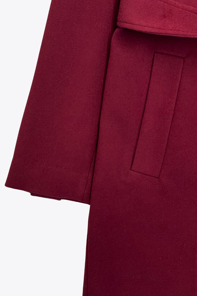 Abrigo largo de fit recto con solapa, manga larga con puños abotonados y bolsillos delanteros con vivos. Cierre frontal con doble cruce de botones. Detalle de abetura posterior en bajo, trabillas y cinturón amarrable del mismo tejido.