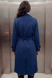 Abrigo trench midi de gamuza, fit recto, con solapa, bolsillos delanteros con vivos, detalle de bata frontal, manga larga con trabillas en puños y hombros, cinturón amarrable del mismo tejido y cierre frontal con doble cruce de botones en contraste.