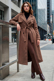 Abrigo trench midi de gamuza, fit recto, con solapa, bolsillos delanteros con vivos, detalle de bata frontal, manga larga con trabillas en puños y hombros, cinturón amarrable del mismo tejido y cierre frontal con doble cruce de botones en contraste.
