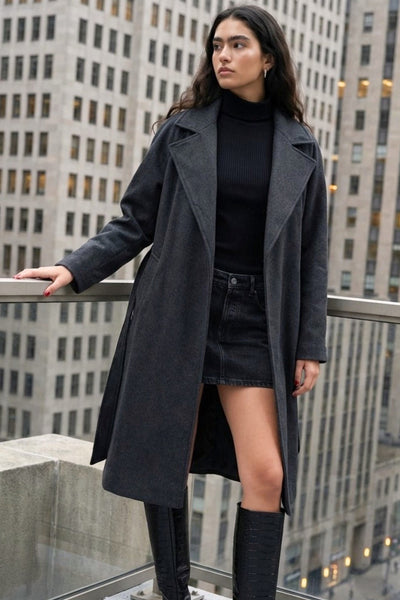 Abrigo largo de corte en a, con solapa, manga larga con puño abotonado en contraste y bolsillos frontales con cartera. Detalle de trabillas, cinturón amarrable del mismo tejido y abertura posterior.