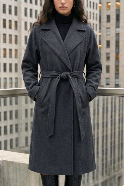 Abrigo largo de corte en a, con solapa, manga larga con puño abotonado en contraste y bolsillos frontales con cartera. Detalle de trabillas, cinturón amarrable del mismo tejido y abertura posterior.