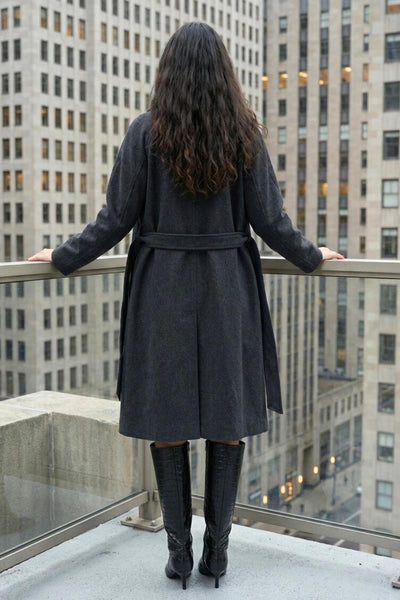 Abrigo largo de corte en a, con solapa, manga larga con puño abotonado en contraste y bolsillos frontales con cartera. Detalle de trabillas, cinturón amarrable del mismo tejido y abertura posterior.