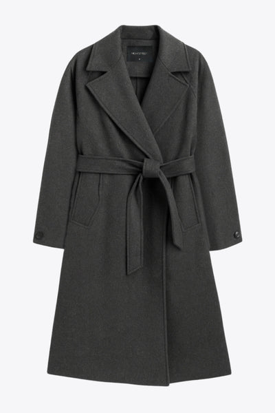 Abrigo largo de corte en a, con solapa, manga larga con puño abotonado en contraste y bolsillos frontales con cartera. Detalle de trabillas, cinturón amarrable del mismo tejido y abertura posterior.