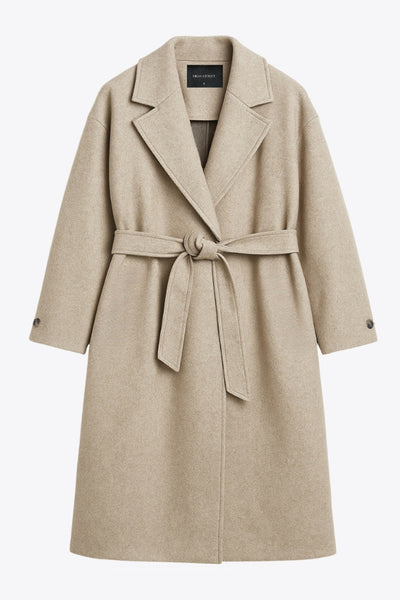 Abrigo largo de corte en a, con solapa, manga larga con puño abotonado en contraste y bolsillos frontales con cartera. Detalle de trabillas, cinturón amarrable del mismo tejido y abertura posterior.