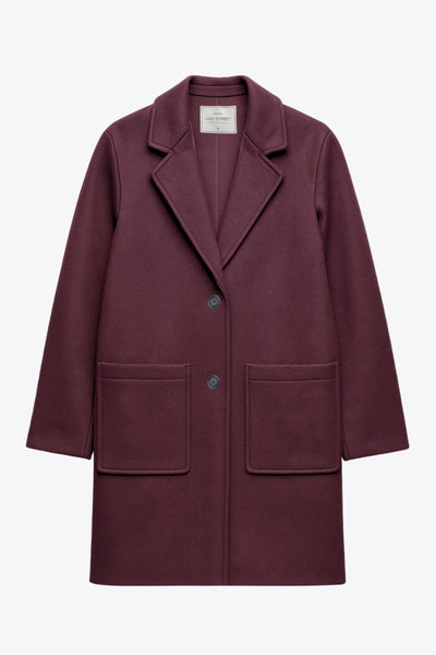 Abrigo largo de fit recto, manga larga, con solapa, bolsillos delanteros de parche y cierre frontal con cruce de botones en contraste.