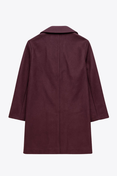 Abrigo largo de fit recto, manga larga, con solapa, bolsillos delanteros de parche y cierre frontal con cruce de botones en contraste.