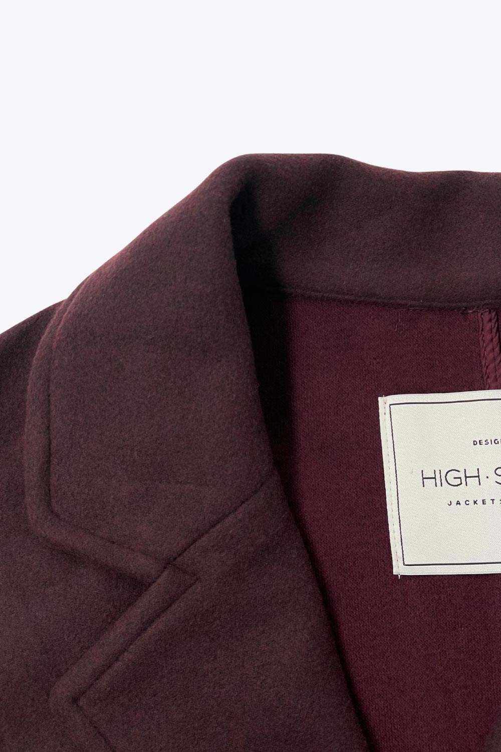 Abrigo largo de fit recto, manga larga, con solapa, bolsillos delanteros de parche y cierre frontal con cruce de botones en contraste.