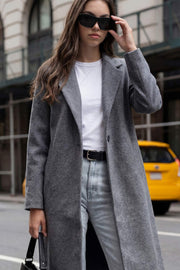 Abrigo largo de fit recto, con solapa, manga larga y cierre frontal con cruce de botón en contraste.