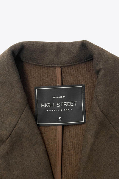 Abrigo largo de fit recto, con solapa, manga larga y cierre frontal con cruce de botón en contraste.