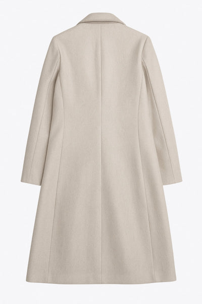 Abrigo largo de fit recto, con solapa y hombreras, manga larga, bolsillos delanteros con vivos y cierre frontal con botones en contraste.