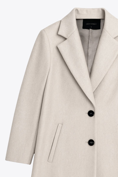 Abrigo largo de fit recto, con solapa y hombreras, manga larga, bolsillos delanteros con vivos y cierre frontal con botones en contraste.