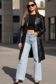 Abrigo trench de efecto piel, fit recto, con solapa, bolsillos delanteros con vivos, detalle de bata delantera y manga larga. Trabillas, cinturón amarrable del mismo tejido y cierre frontal con doble cruce de botón.