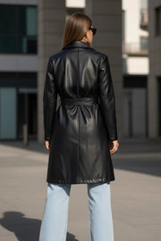 Abrigo trench de efecto piel, fit recto, con solapa, bolsillos delanteros con vivos, detalle de bata delantera y manga larga. Trabillas, cinturón amarrable del mismo tejido y cierre frontal con doble cruce de botón.