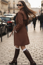Abrigo trench corto de fit recto, con cuello solapa, bolsillos delanteros con vivos, detalle de bata trasera y manga larga. Trabillas, cinturón amarrable del mismo tejido y cierre frontal con doble cruce de botones en contraste. Detalle de trabilla y botón en hombros, bata trasera, cuello y puños.
